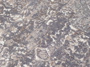 Nahaufnahme eines Designer Teppichs mit abstraktem Muster in Grau- und Beigetönen, von oben betrachtet.