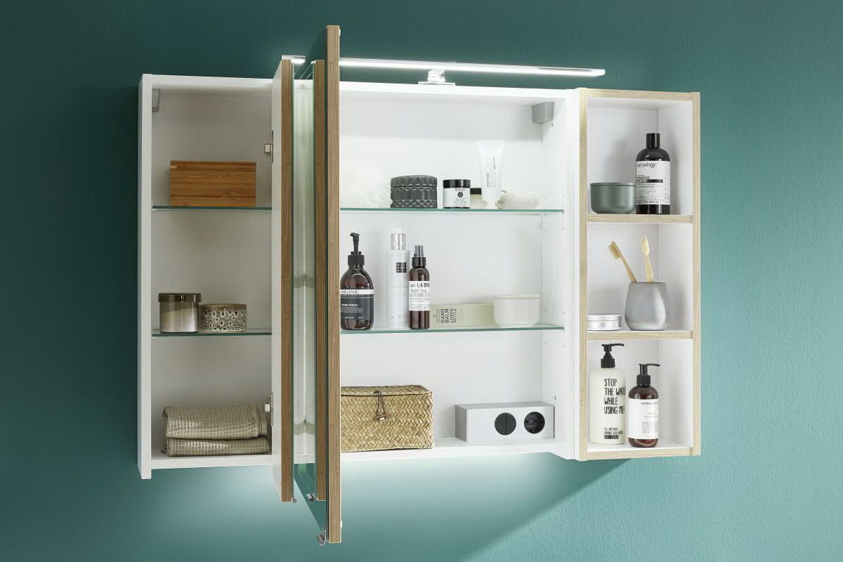 Badezimmerschrank mit offenen und geschlossenen Fächern, gefüllt mit Pflegeprodukten und Accessoires, aus frontaler Perspektive.