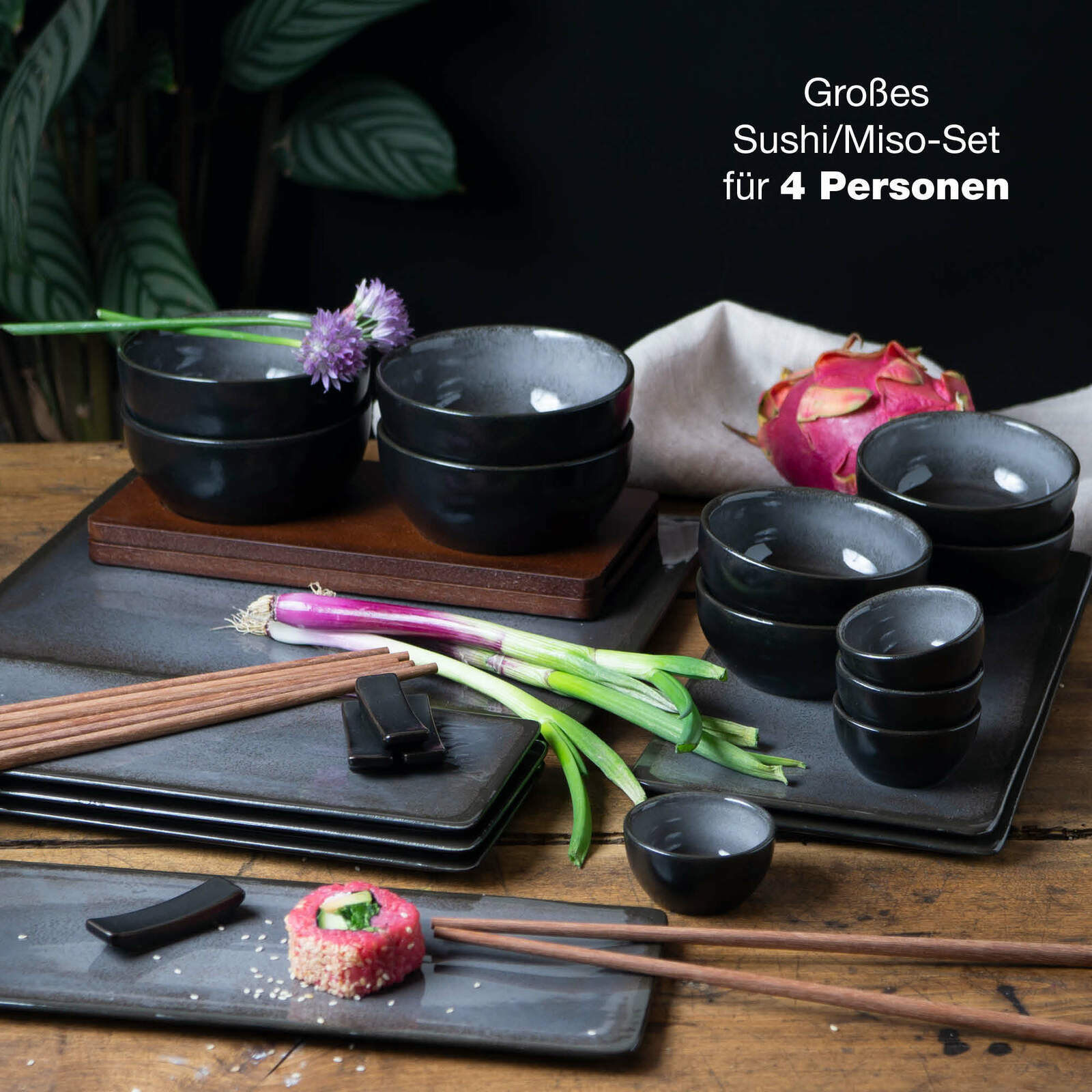 29-teiliges Sushi-Set in Anthrazit für 4 Personen, bestehend aus Schalen und Tellern, präsentiert auf einem Holztisch mit frischen Zutaten und Essstäbchen, aus der Vogelperspektive.