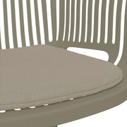 Nahaufnahme eines beigen Stapelsessels mit gepolstertem Sitzkissen, seitliche Perspektive