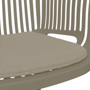 Nahaufnahme eines beigen Stapelsessels mit gepolstertem Sitzkissen, seitliche Perspektive