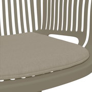 Nahaufnahme eines beigen Stapelsessels mit gepolstertem Sitzkissen, seitliche Perspektive