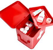 Rote Metall-Medizinbox mit geöffnetem Deckel, gefüllt mit Verbandsmaterial und Desinfektionsmittel, aus der Vogelperspektive fotografiert.