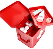 Rote Metall-Medizinbox mit geöffnetem Deckel, gefüllt mit Verbandsmaterial und Desinfektionsmittel, aus der Vogelperspektive fotografiert.