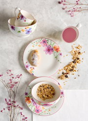 Frühstücks-Set mit floralem Design, bestehend aus Tassen, Schalen und Tellern, von oben fotografiert.