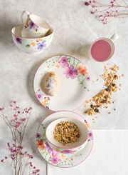 Frühstücks-Set mit floralem Design, bestehend aus Tassen, Schalen und Tellern, von oben fotografiert.
