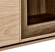 Detailaufnahme eines Möbelstücks in Holzoptik mit Glaseinsatz, Ansicht schräg von vorne auf die Ecke des Rahmens