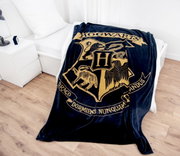 Weiche Wellsoft-Flauschdecke mit Hogwarts-Wappen, drapiert auf einem Bett in einem modernen Schlafzimmer.