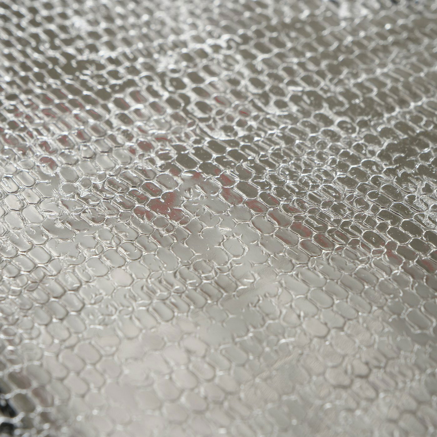 Nahaufnahme eines Tabletts aus Aluminium mit strukturierter Oberfläche, von oben betrachtet.