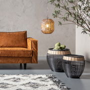 Beistelltisch Set aus schwarzem Drahtgeflecht mit hellem Holzrand, im Wohnzimmer neben einem braunen Sofa, aus seitlicher Perspektive fotografiert.