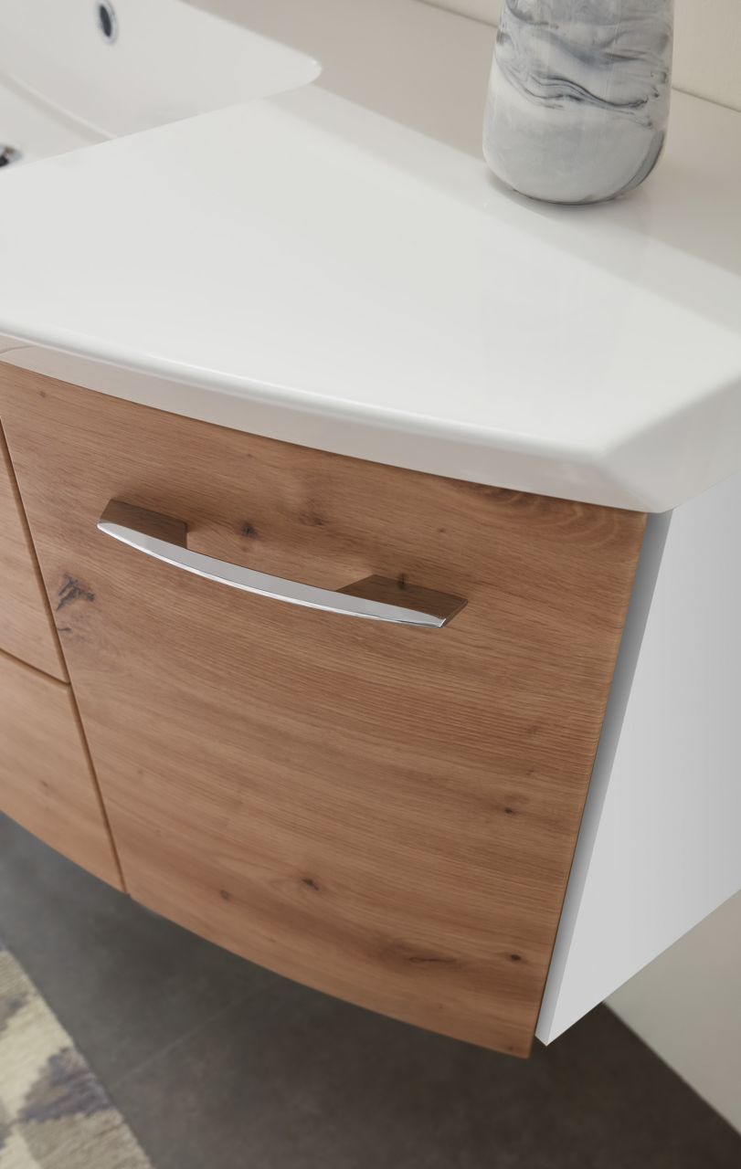 Nahaufnahme einer Badkombination mit Holzfront und weißer Waschtischplatte, seitliche Perspektive.