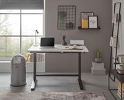 Moderner E-Schreibtisch in einem stilvollen Büro mit Blick auf ein großes Fenster, ausgestattet mit einem Laptop, einer Lampe und dekorativen Elementen.