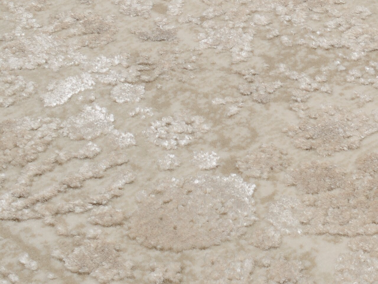 Nahaufnahme eines Designer Teppichs mit beigem und cremefarbenem Muster, aus der Vogelperspektive fotografiert.