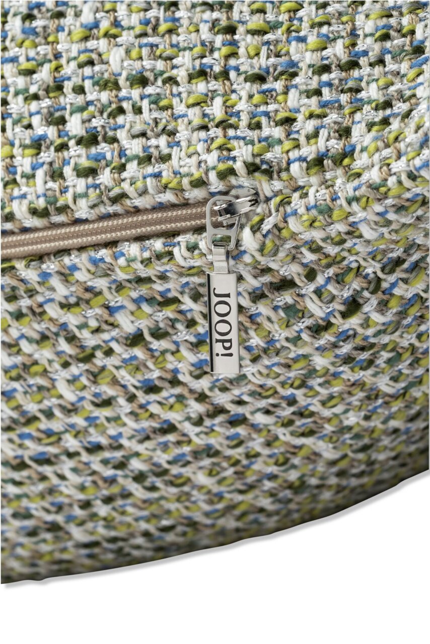 Nahaufnahme einer Zierkissenhülle mit grobem, mehrfarbigem Gewebe und einem Reißverschluss mit dem Schriftzug 'JOOP!'