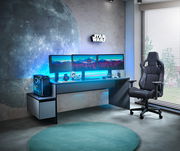 Gaming-Setup mit beleuchtetem Tisch, drei Monitoren, Towerunit und Gaming-Stuhl aus seitlicher Perspektive