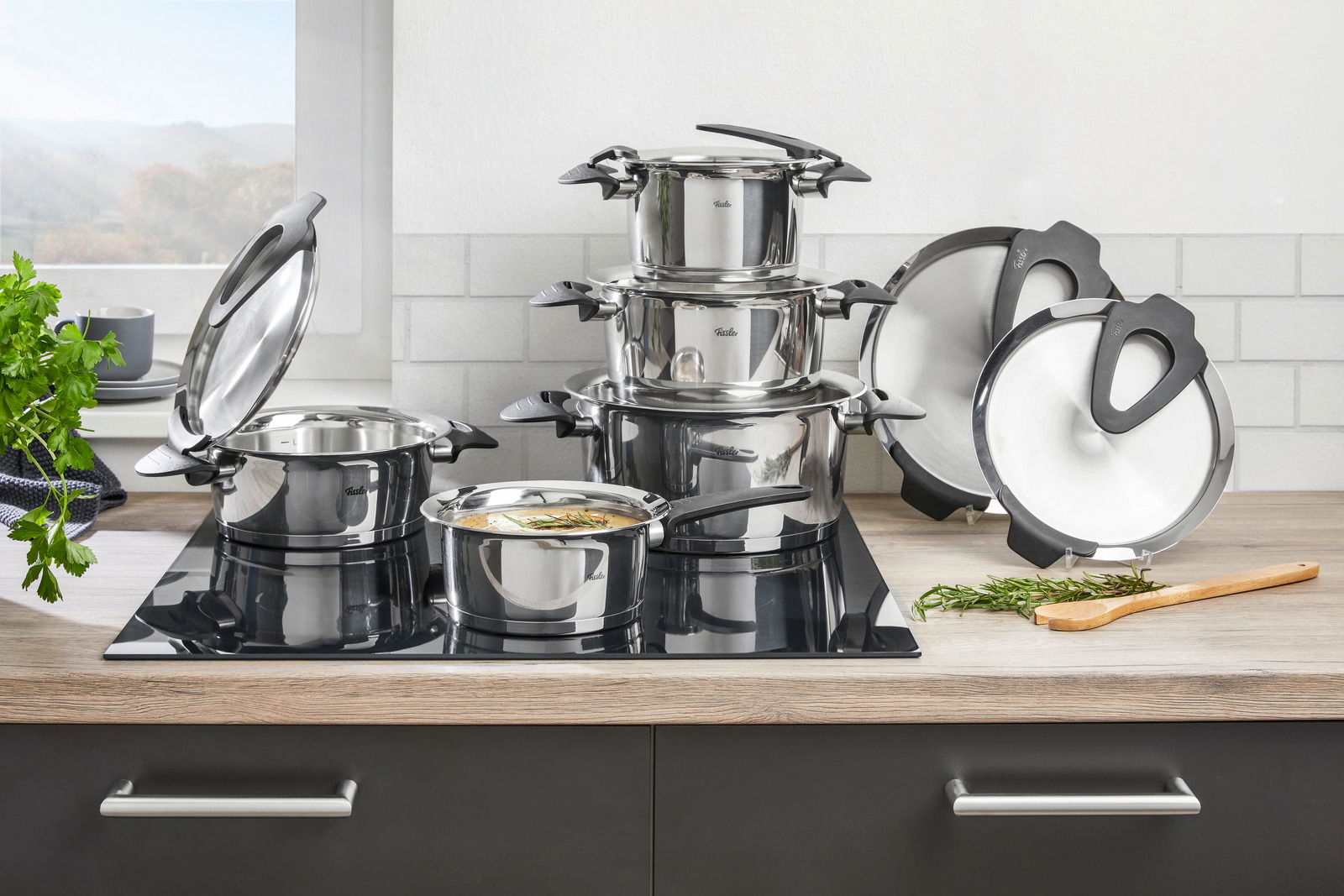 Topfset Intensa 5-tlg. aus Edelstahl, bestehend aus mehreren Töpfen mit Deckeln, auf einem modernen Herd in einer Küche. Perspektive von vorne.