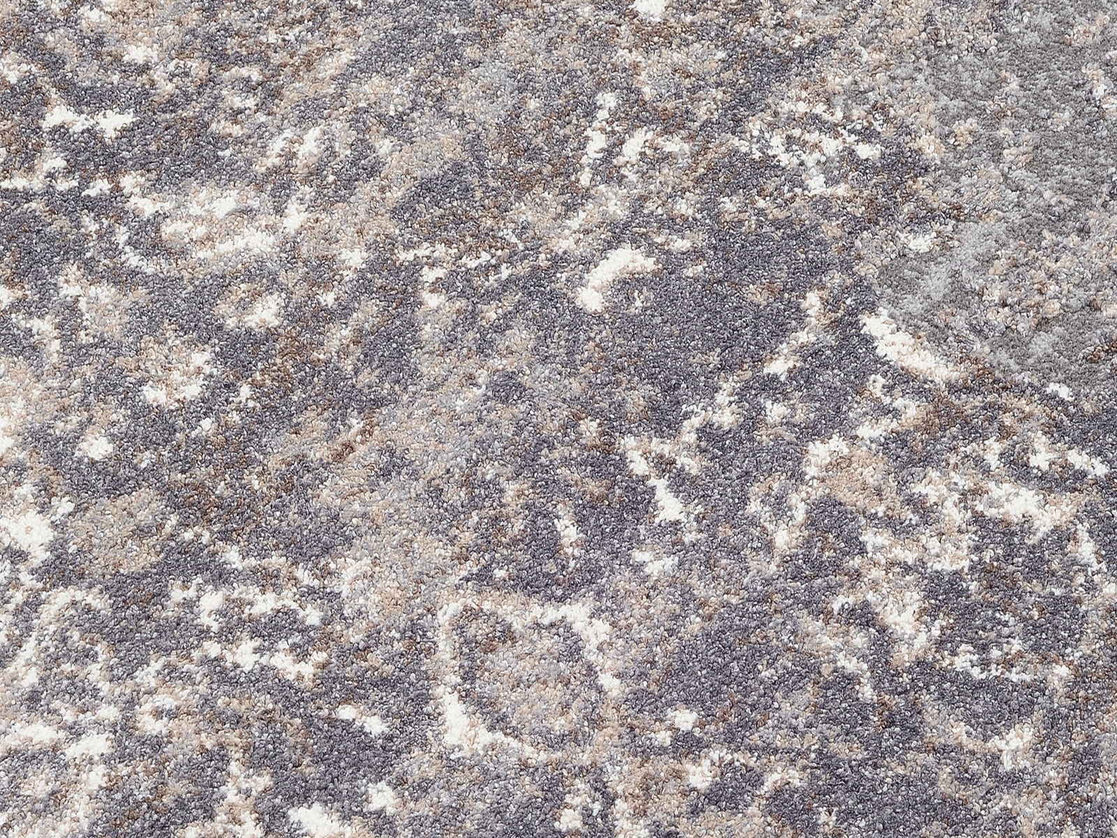 Nahaufnahme eines Designer Teppichs mit abstraktem Muster in Grau- und Beigetönen, von oben betrachtet.