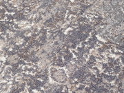 Nahaufnahme eines Designer Teppichs mit abstraktem Muster in Grau- und Beigetönen, von oben betrachtet.