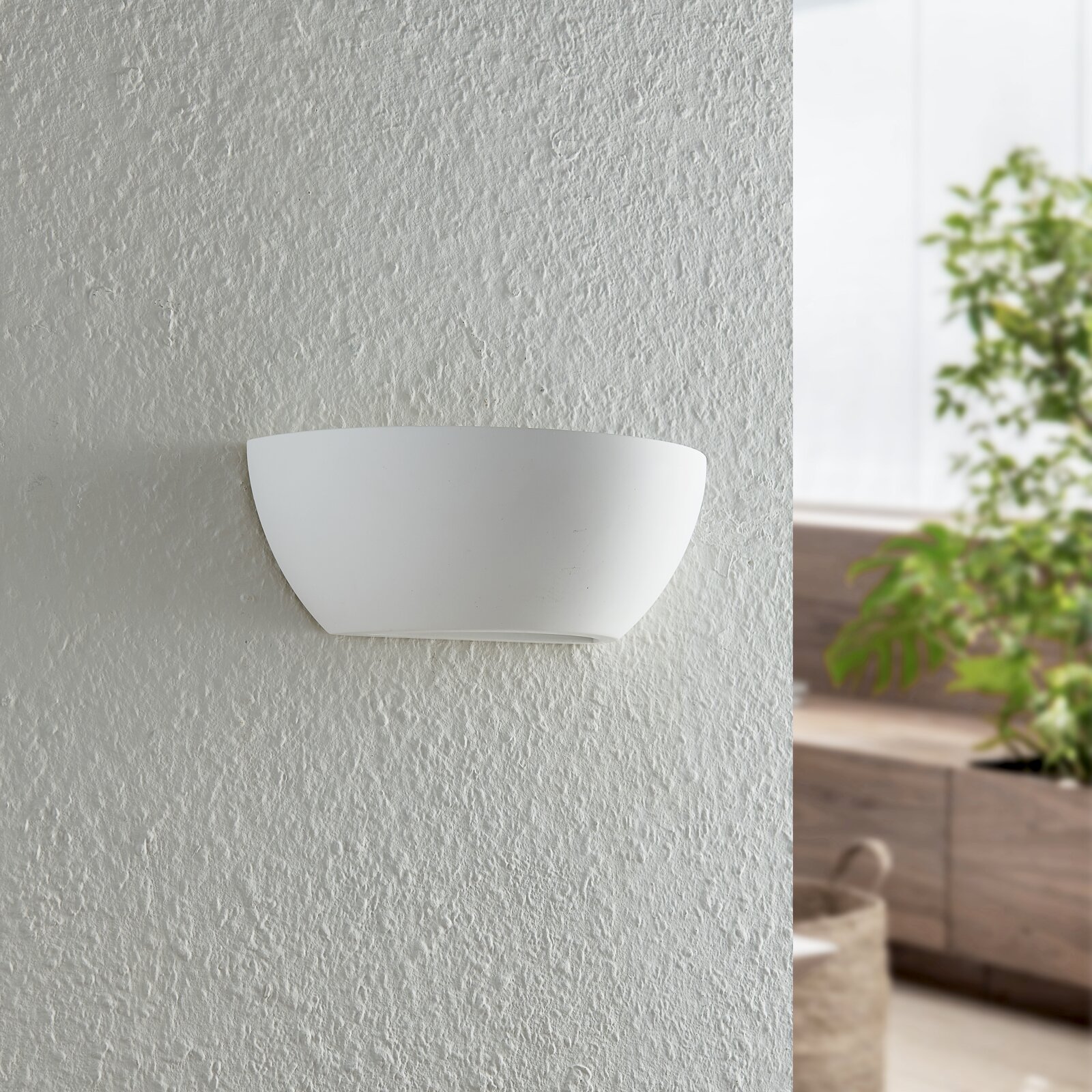 Moderne weiße Wandleuchte in halbrunder Form, frontal an einer strukturierten Wand montiert.