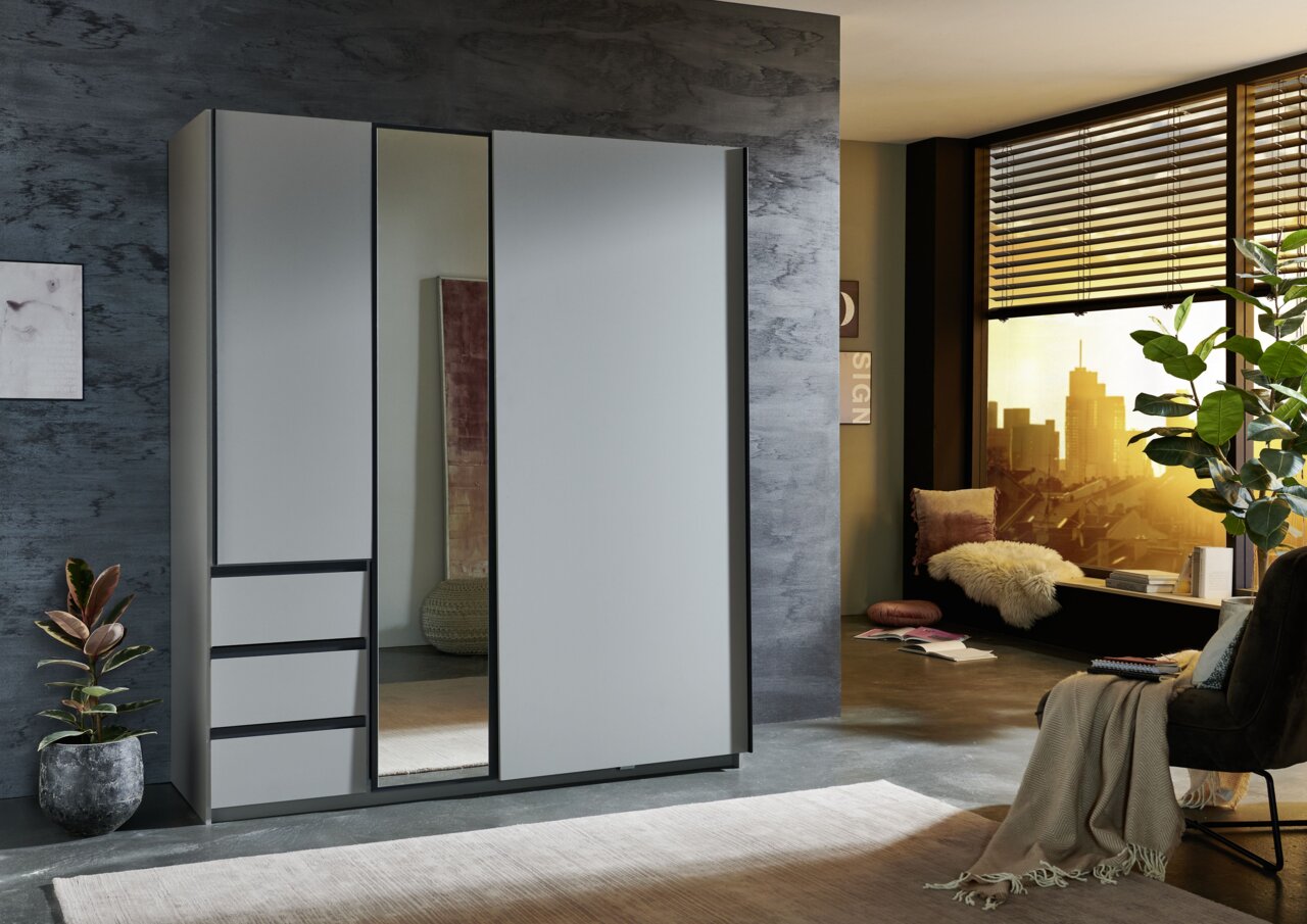 Moderner Schwebetürenschrank mit zwei Türen, einer davon mit Spiegel, in einem stilvollen Raum mit Blick auf die Stadt. Perspektive von schräg vorne.