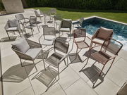 Mehrere Stapelsessel in verschiedenen Farben stehen auf einer Terrasse neben einem Pool, fotografiert aus der Vogelperspektive.