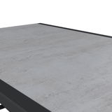 Nahaufnahme eines modernen Gartentisches mit grauer Steinoptik-Oberfläche, perspektivisch von oben betrachtet.