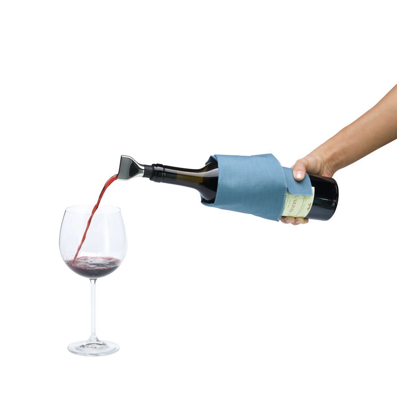 Een hand houdt een wijnfles met schenktuit vast, waaruit rode wijn in een glas wordt geschonken, gezien vanuit een zijdelingse hoek.