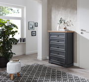 Schubkastenkommode in einem modernen Wohnzimmer, seitliche Perspektive, mit fünf Schubladen und einer Holzplatte, dekoriert mit einer Vase und Büchern.