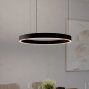 Zwarte, ringvormige LED-hanglamp met warmwit licht, recht voor de eettafel opgehangen, gezien vanuit een licht zijdelingse hoek van onderaf