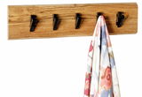 Wandgarderobe aus Holz mit fünf schwarzen Haken, frontal abgebildet, mit einem bunten Tuch an einem Haken.