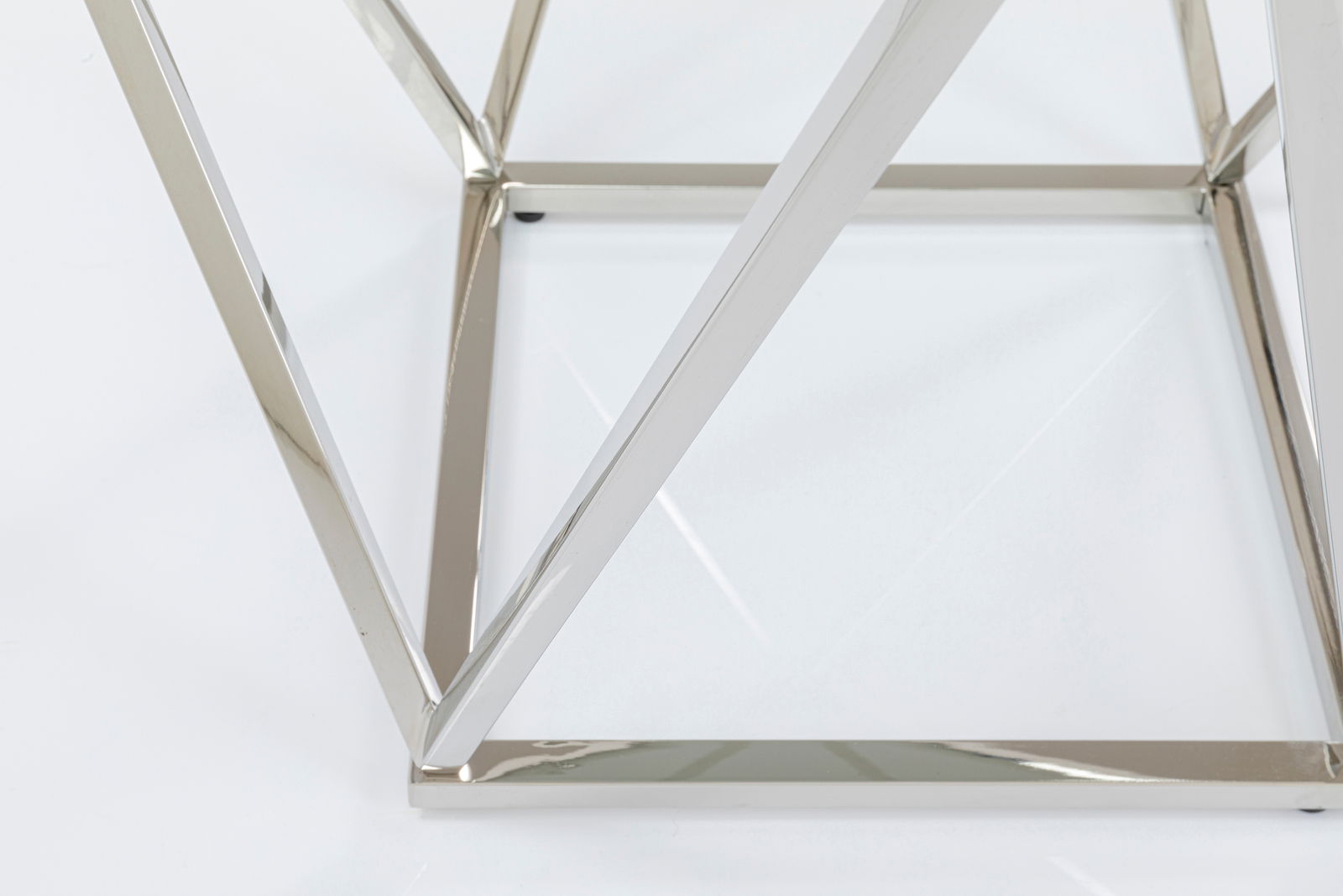 Nahaufnahme eines modernen Beistelltisches mit verchromtem Metallrahmen und Glasplatte, von unten fotografiert.