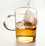 Theeglas Novo 360 ml met oor, gefotografeerd vanaf de zijkant terwijl er heet water over een theezakje wordt gegoten.