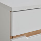 Nahaufnahme einer weißen Kommode mit Holzdetails, seitliche Perspektive