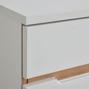 Nahaufnahme einer weißen Kommode mit Holzdetails, seitliche Perspektive