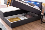 Boxbett mit hochgeklappter Matratze, darunter Stauraum mit Decken und Kissen, seitliche Perspektive