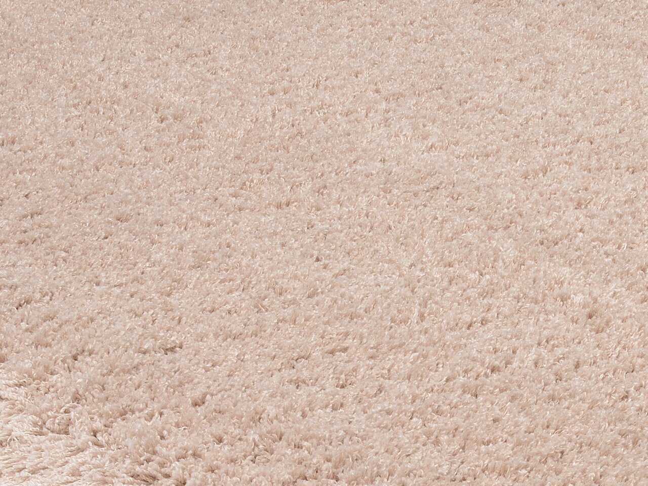 Nahaufnahme eines weichen, cremefarbenen Teppichs mit flauschiger Textur, perspektivisch von oben betrachtet.