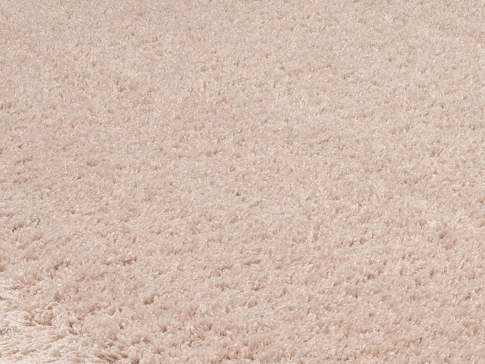 Nahaufnahme eines weichen, cremefarbenen Teppichs mit flauschiger Textur, perspektivisch von oben betrachtet.