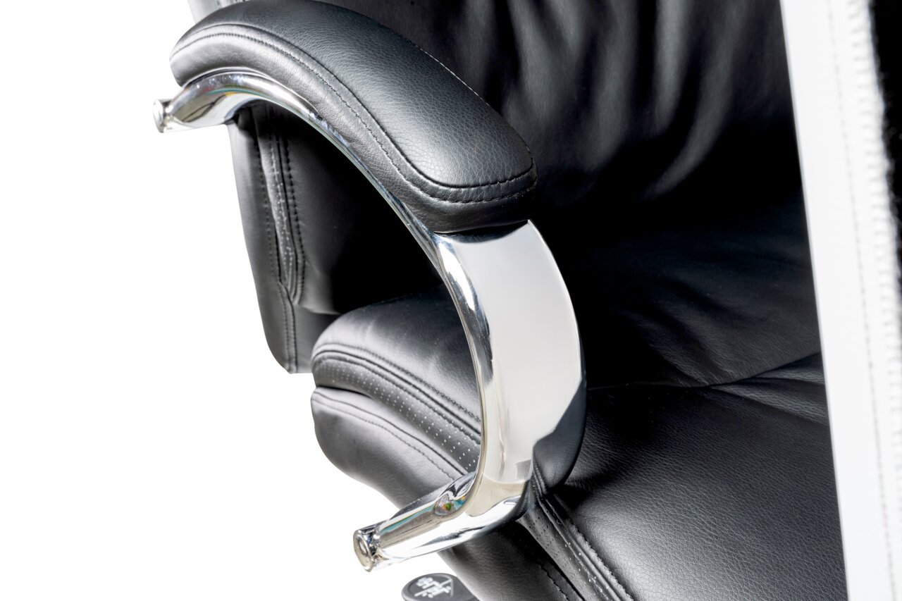 Nahaufnahme eines schwarzen Chefsessels mit gepolsterter Armlehne und verchromtem Gestell, seitliche Perspektive