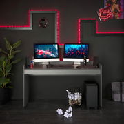 Moderner Schreibtisch in einem stilvollen Gaming-Setup mit zwei Monitoren, Tastatur und Maus, umgeben von LED-Beleuchtung und Dekorationen, aus der Frontalperspektive.
