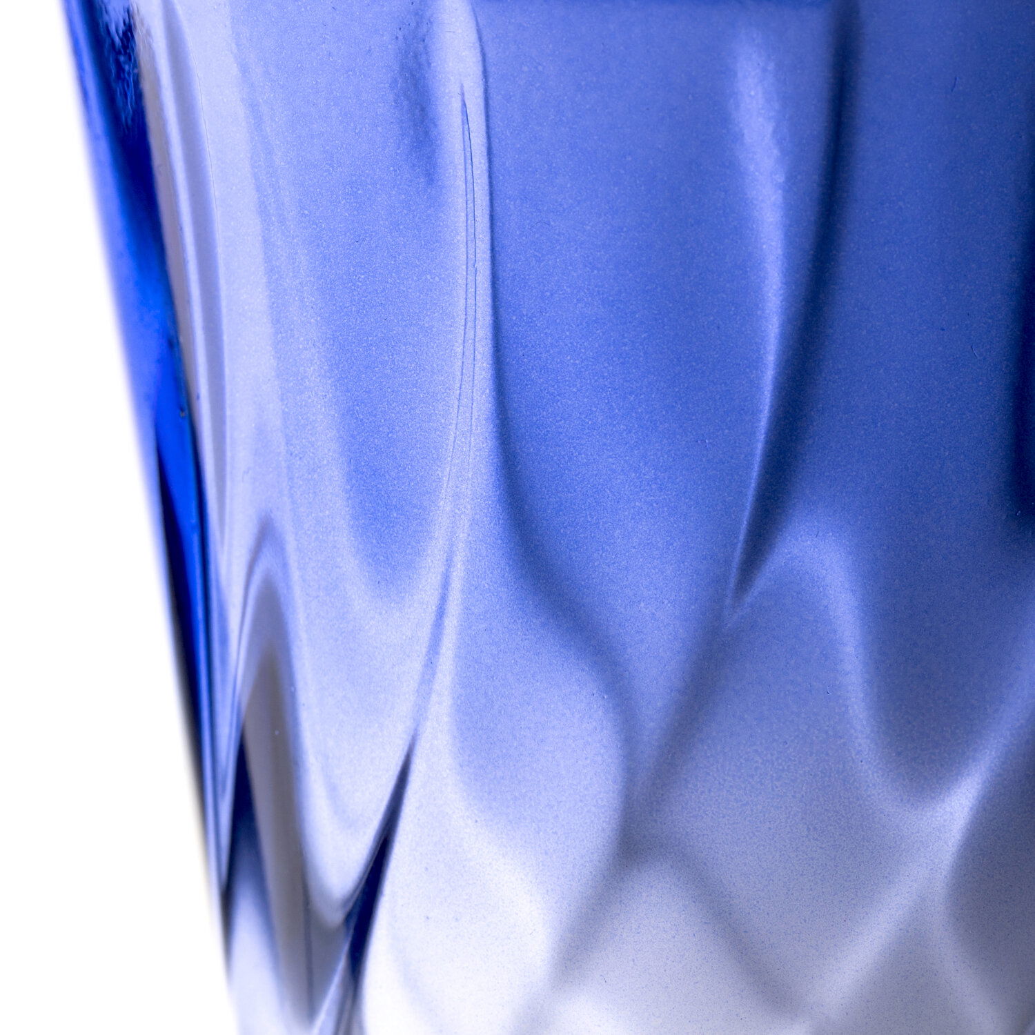 Nahaufnahme eines blauen Trinkglases mit gedrehtem Design, seitliche Perspektive