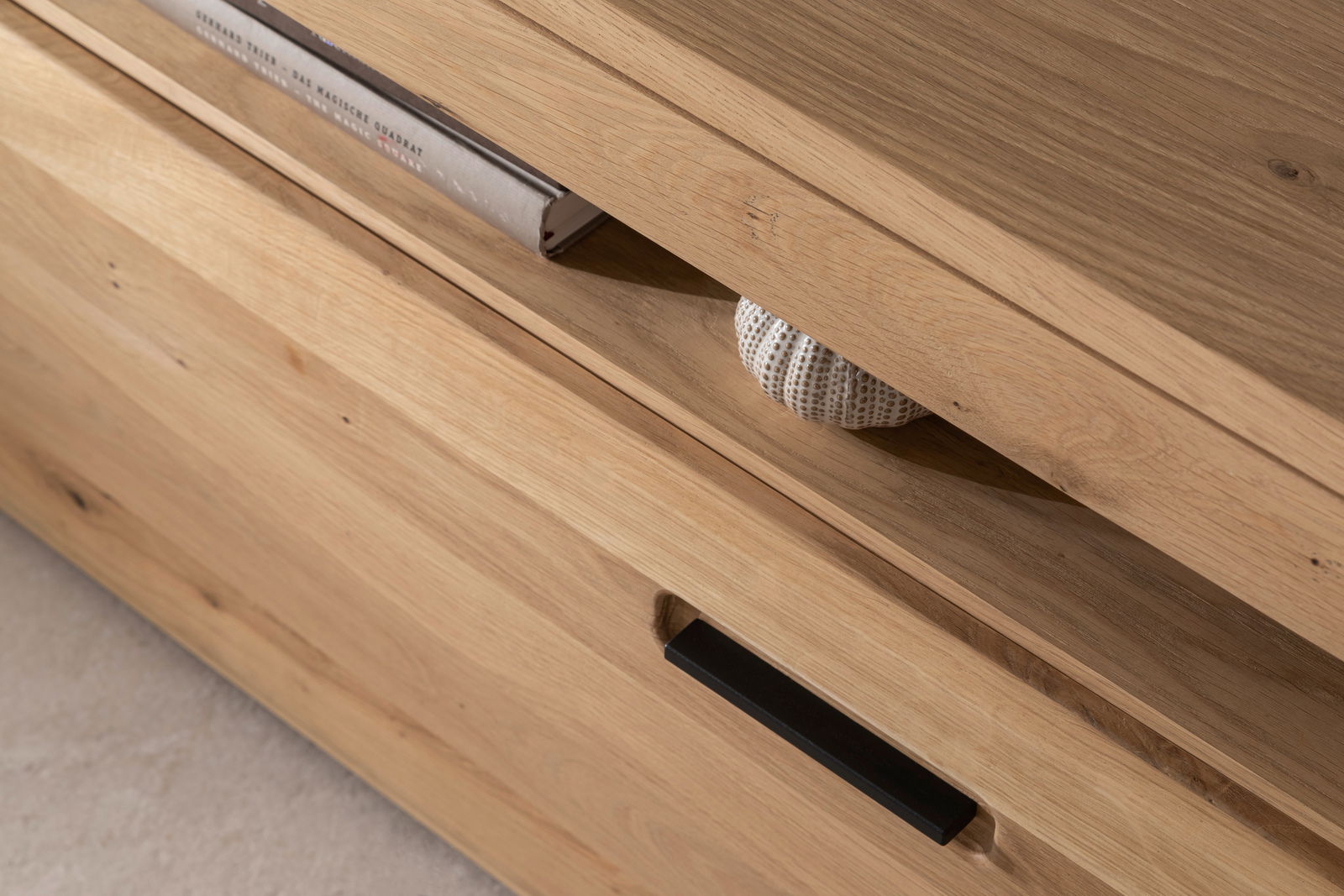 Nahaufnahme eines TV-Elements aus Holz mit sichtbarer Schublade und dekorativem Buch. Perspektive von schräg oben.