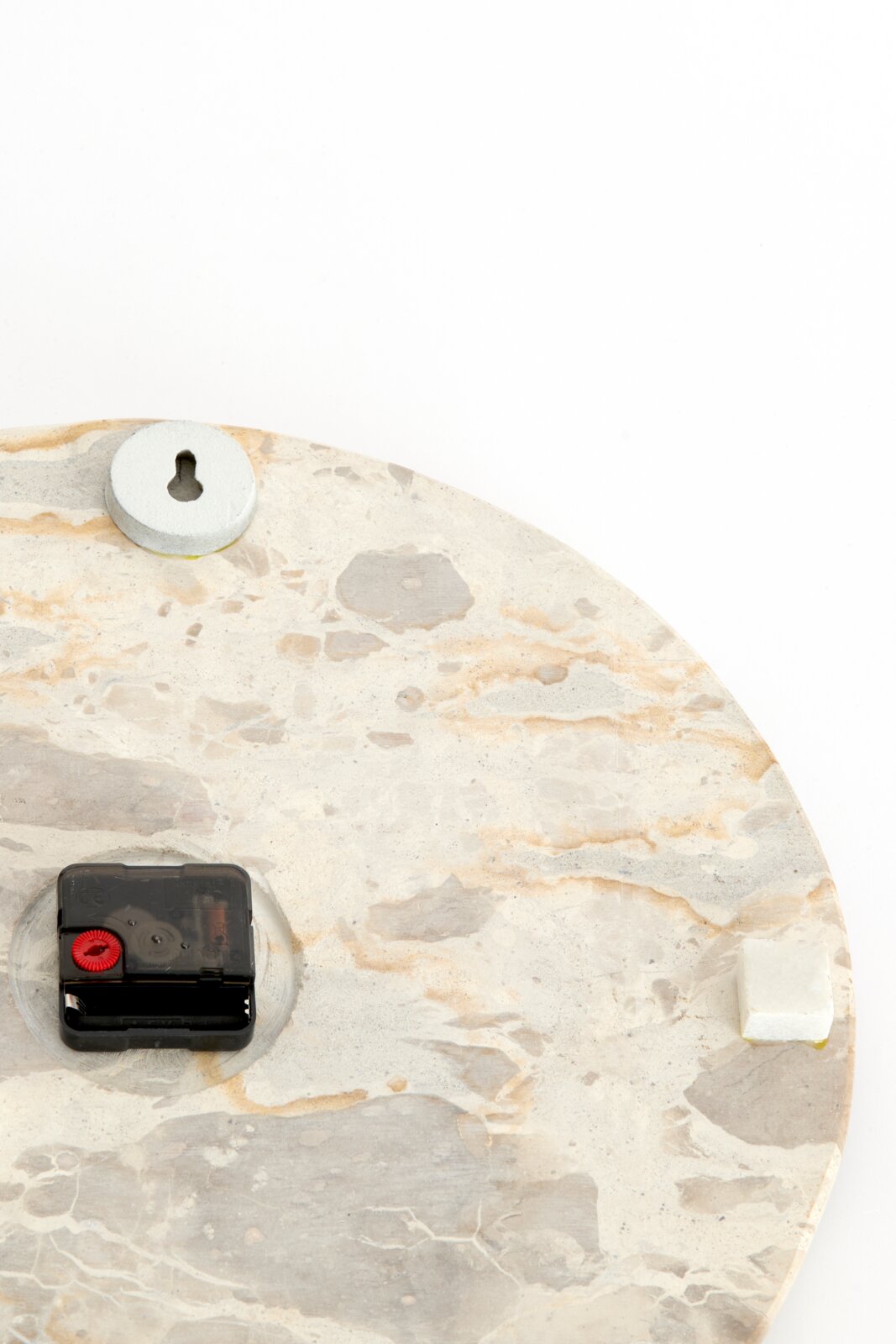Achteraanzicht van een ronde wandklok met lichte natuursteenlook, zwart uurwerk, sleutelgatophanging en beschermende afstandhouders