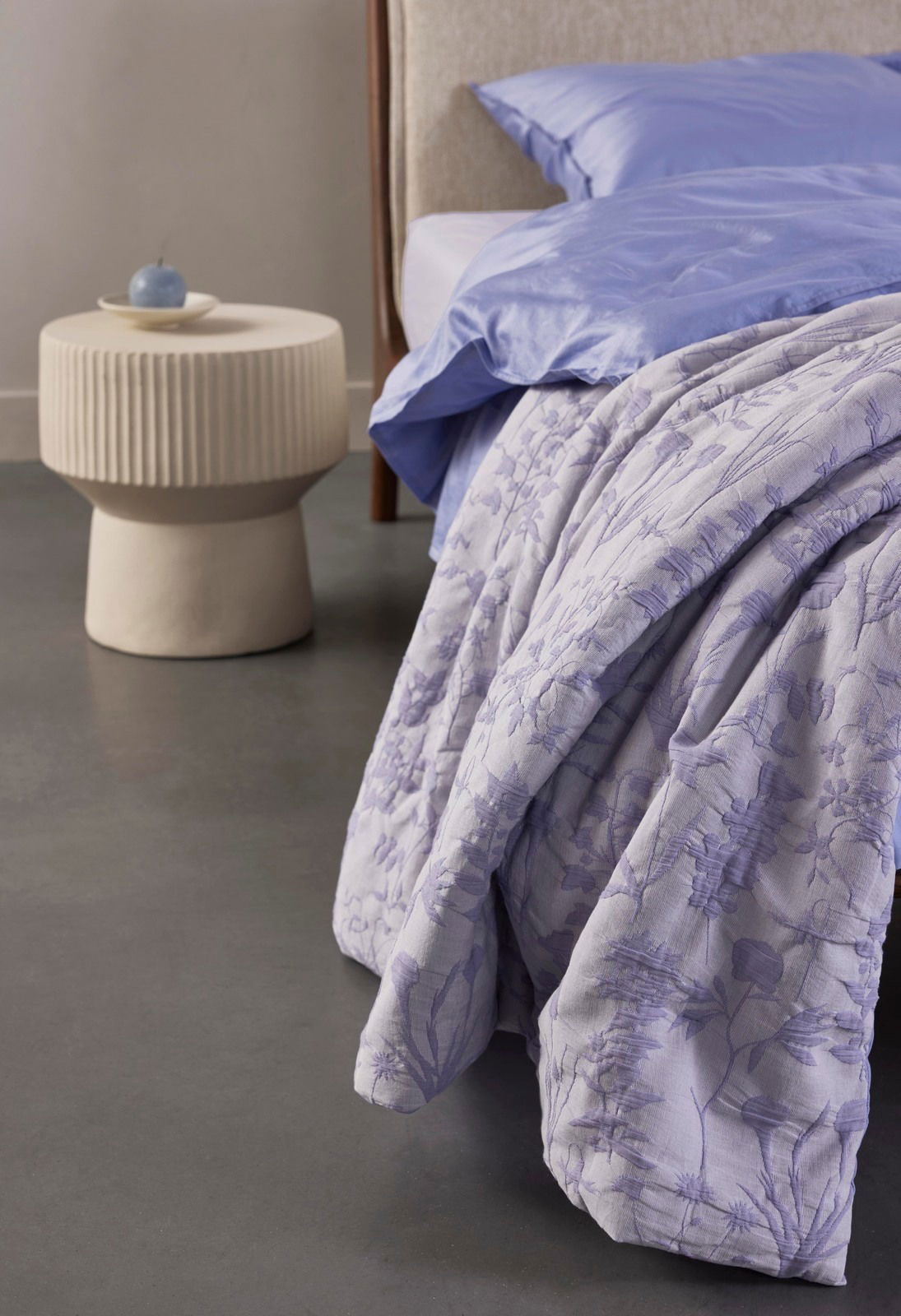 Bettwäsche in Fliederfarben mit floralem Muster, auf einem Bett drapiert, seitliche Perspektive
