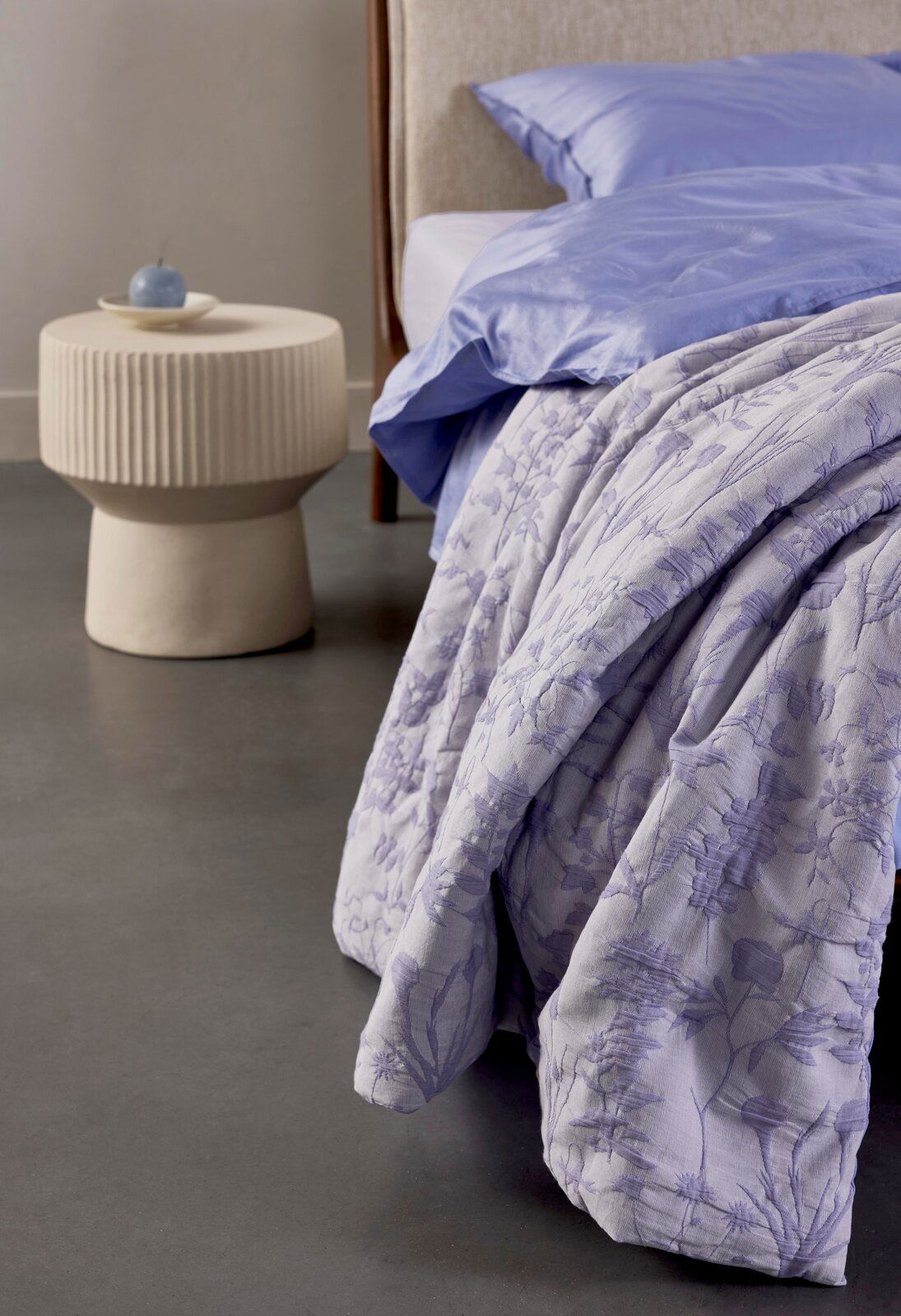 Bettwäsche in Fliederfarben mit floralem Muster, auf einem Bett drapiert, seitliche Perspektive