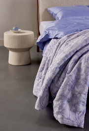 Bettwäsche in Fliederfarben mit floralem Muster, auf einem Bett drapiert, seitliche Perspektive