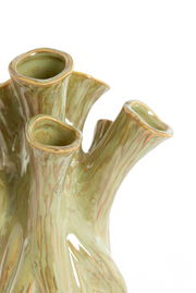 Nahaufnahme einer grünen, organisch geformten Vase mit mehreren Öffnungen und einer texturierten Oberfläche, die an Baumrinde erinnert.