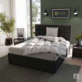 Gemütliches Schlafzimmer mit einem modernen Bett, das mit einer weißen, gesteppten Cassettendecke und einem passenden Kissen ausgestattet ist. Die Perspektive zeigt das Bett von schräg vorne, umgeben von stilvoller Dekoration und einem großen Fenster im H