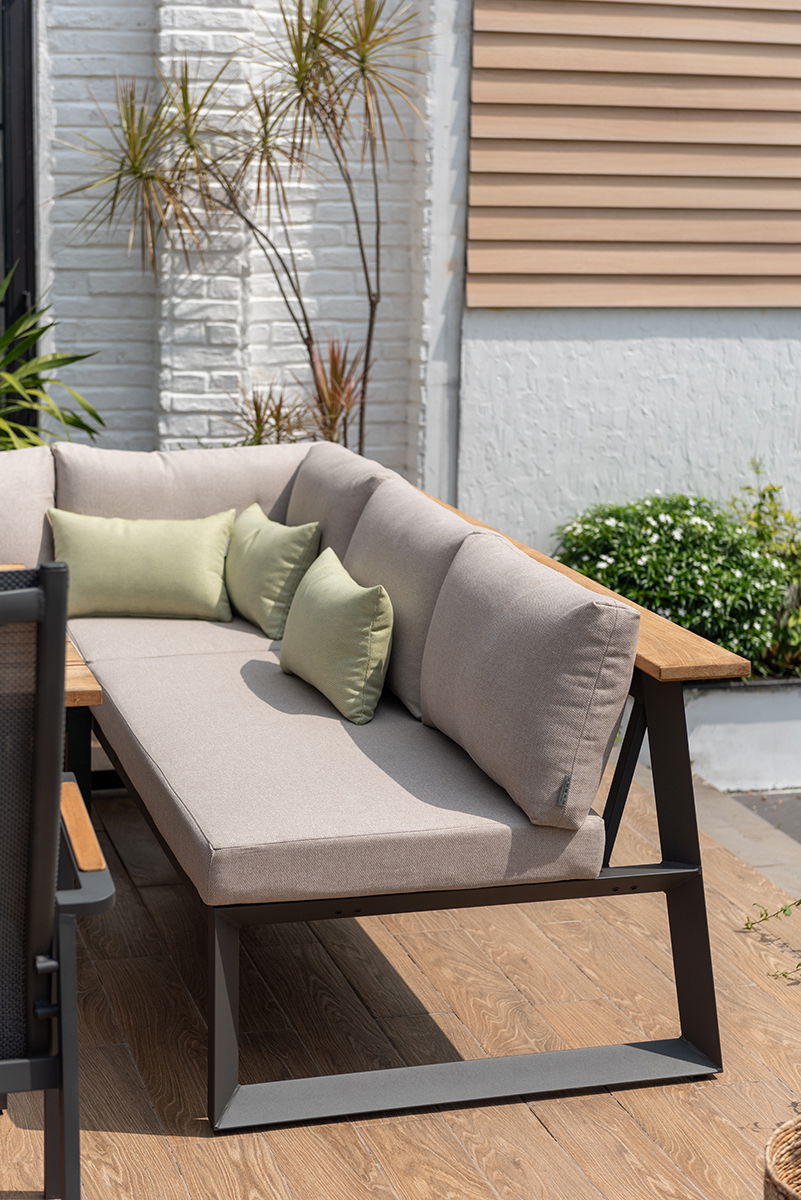 Moderne Outdoor-Sitzbank mit beigen Polstern und grünen Kissen, seitliche Perspektive