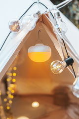 Akku-Leuchtmittel in einem Zelt, von innen betrachtet, umgeben von dekorativen Glühbirnen.