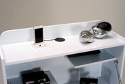 Weißer Sekretär mit Ablagefläche, auf der ein Smartphone in einer Dockingstation und eine silberne Deko-Schnecke stehen. Perspektive von oben.
